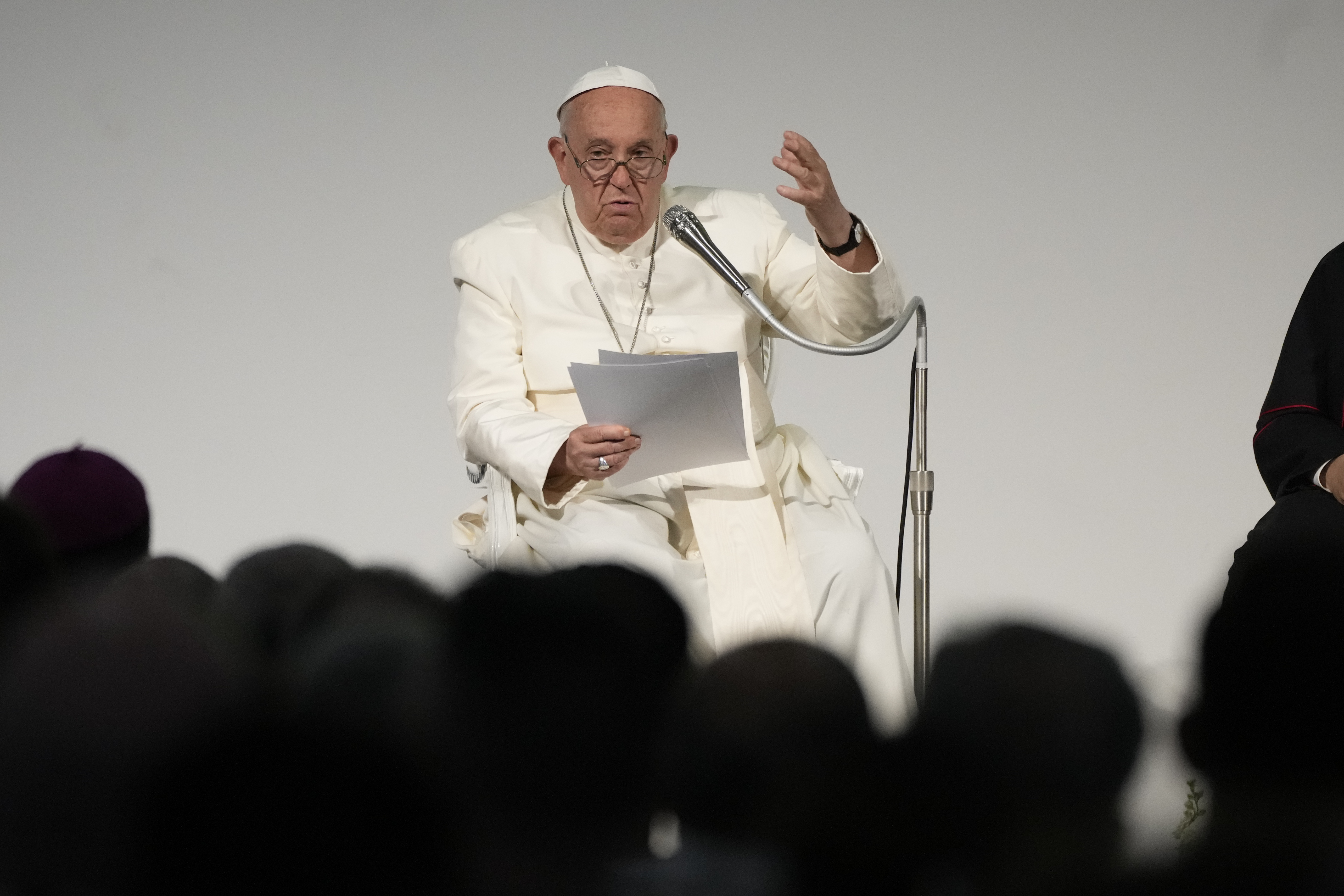 Pope Francis, seated, reads remarks