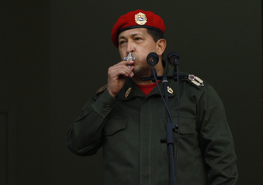Chavez, in military regalia, kisses crucifix. 