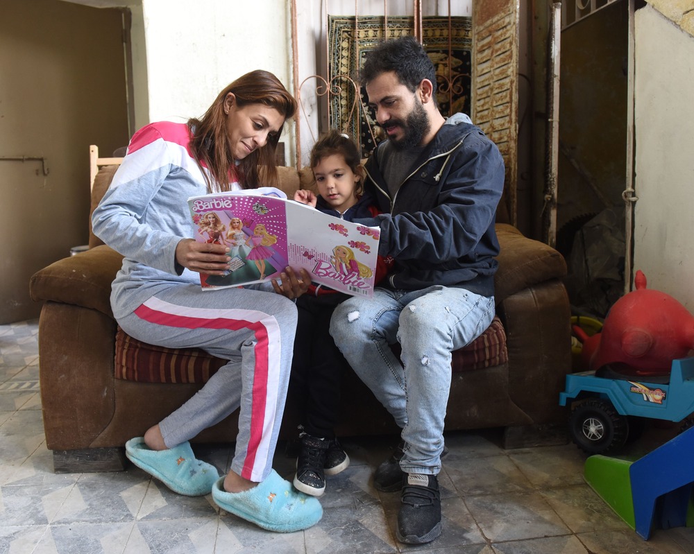 Man and woman read with little girl. 