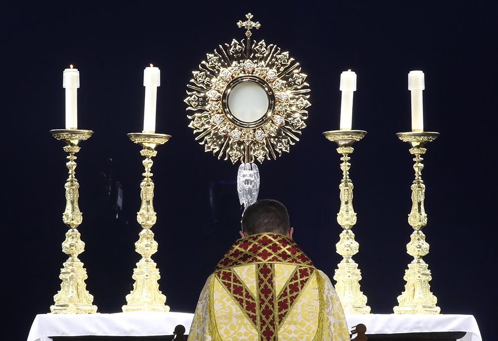 Bishop Andrew Cozzens of Crookston, Minnesota, chairman of the board of the National Eucharistic Congress Inc., kneels in prayer before the monstrance during Eucharistic adoration at the opening revival night of the 10th National Eucharistic Congress, July 17 at Lucas Oil Stadium in Indianapolis. (OSV News/Bob Roller)