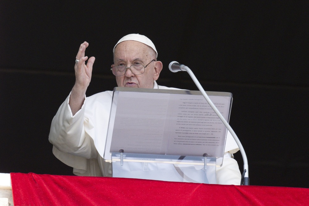 Pope at lectern with hand raised in blessing. 