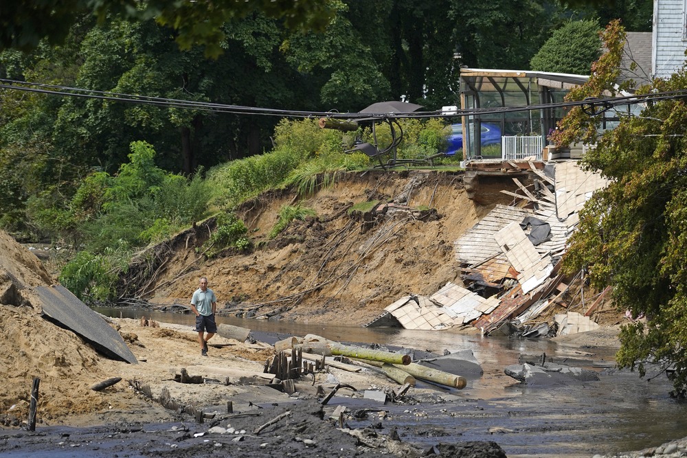 Man walks though enormous washed out gully.