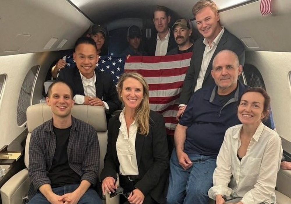 Evan Gershkovich, Paul Whelan and Alsu Kurmasheva, who were detained in Russia, pose with others aboard an aircraft after they were released, in this undated handout photograph obtained on Aug. 1. 