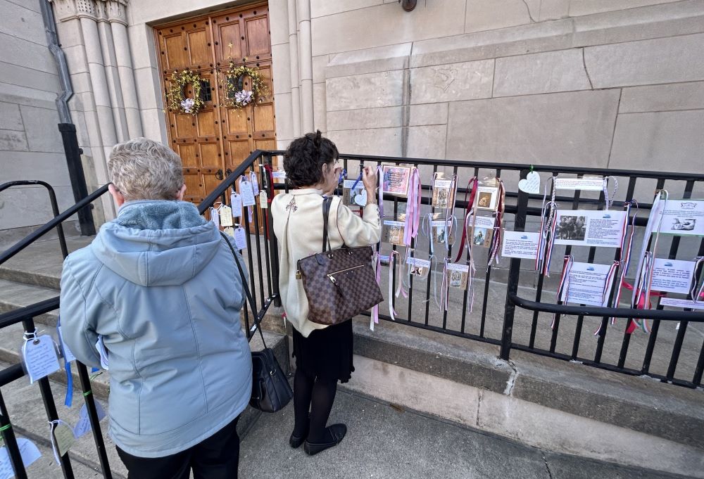 Women place ribbons and messages of support for those who have suffered abuse on the railing outside the Cathedral of St. Joseph in Wheeling, West Virginia.