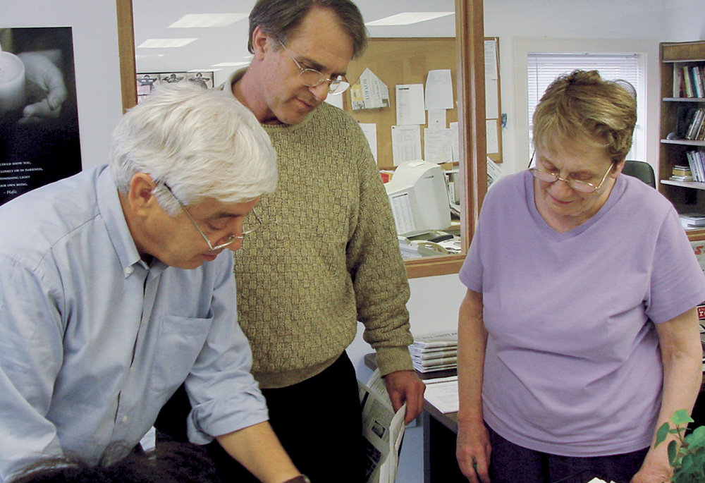 Then-NCR editor Tom Roberts, publisher Tom Fox and copy editor Patty McCarty review pages before sending them to Tribune Publishing to be printed, in this 2004 photo. (NCR photo/Toni-Ann Ortiz)