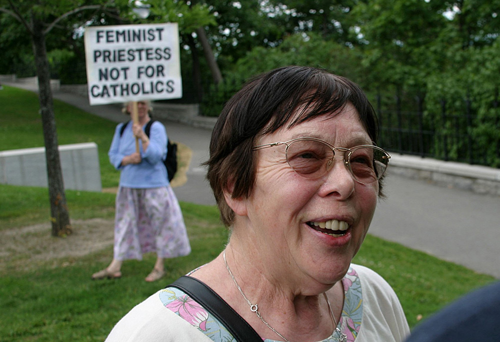 Ida Raming, one of seven women ordained to the Catholic priesthood on the Danube River in 2002, speaks to reporters on Parliament Hill in Ottawa, in this July 22, 2005, file photo. Diane Watts, national president of Women for Life, Faith and Family, holds a protest sign in the background. Raming was excommunicated following her ordination. (CNS/Art Babych)