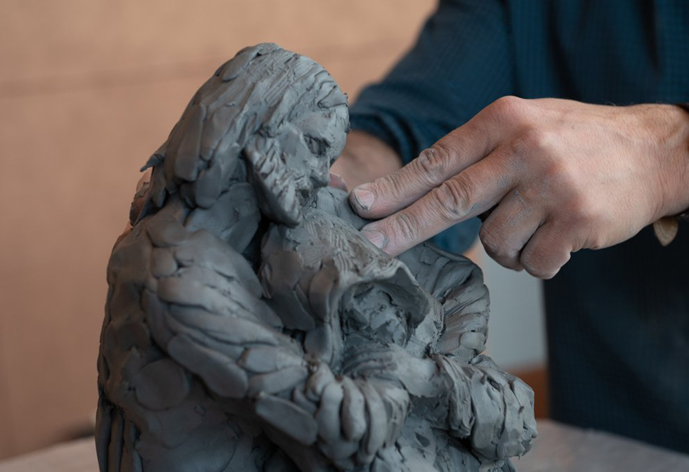 Canadian Catholic artist Tim Schmalz, a native of St. Jacobs, Ontario, sculpts a figure of Jesus embracing a homeless person Sept. 27, 2022, during the annual national gathering of Catholic Charities agencies at the Hilton Baltimore Inner Harbor on Sept. 27-29. (CNS/Catholic Review/Kevin J. Parks)