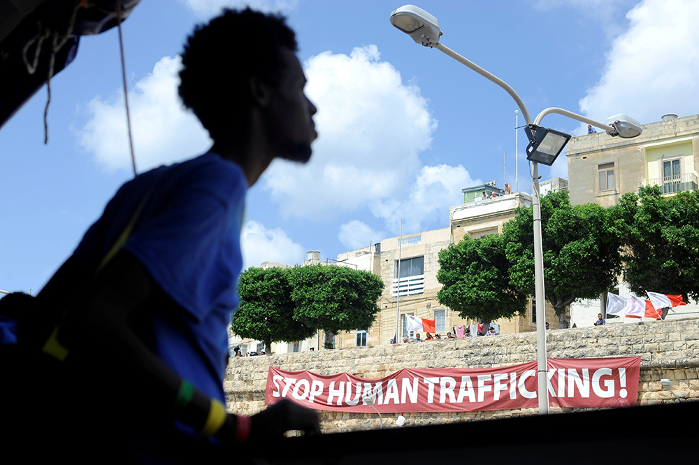 A man walks past a banner reading "Stop Human Trafficking!" in 2018 in Valletta, Malta. (OSV News/Reuters/Guglielmo Mangiapane)