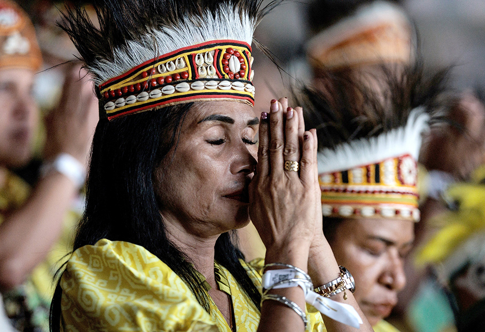 A woman prays as Pope Francis celebrates Mass at Gelora Bung Karno Stadium in Jakarta, Indonesia, on Sept. 5. (OSV News/Yasuyoshi Chiba, pool via Reuters)