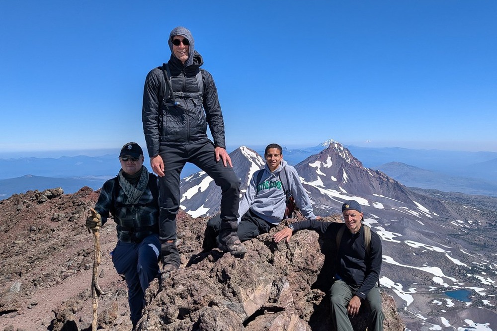 The four stand or sit, in the background is enormous vista.