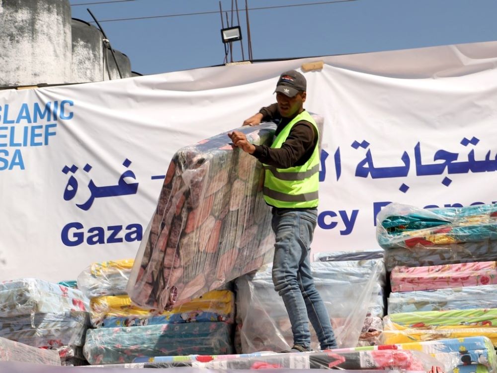 A humanitarian aid worker unloads mattresses supplied by Catholic Relief Services in Rafah, in the southern Gaza Strip, March 21. The mattresses will be distributed to people displaced in war-torn Gaza. (OSV News/Mohammad Al Hout for CRS)