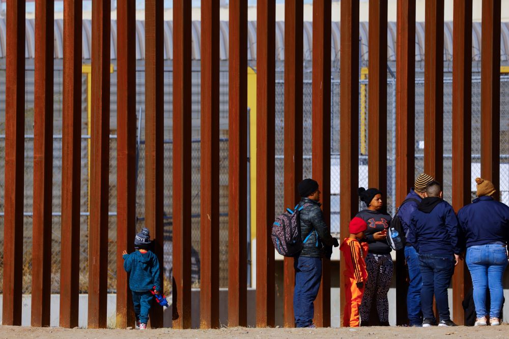 George, 5, a migrant boy from Venezuela traveling with his family, looks through the border wall as family members line up to request asylum in El Paso, Texas, Dec. 27, 2022. (OSV News/Reuters/Jose Luis Gonzalez)