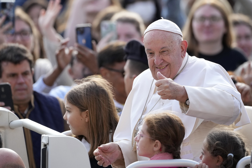 Francis seated in popemobile, smiles and gives thumbs up.