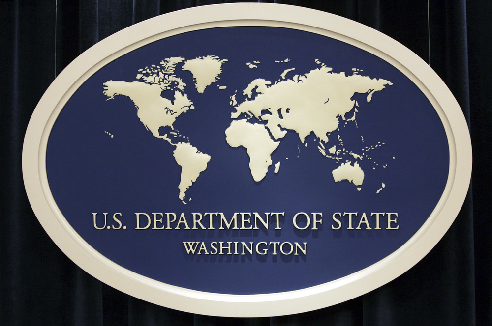 Blue and off-white oval sign with global map, reading "U.S Department of State, Washington."