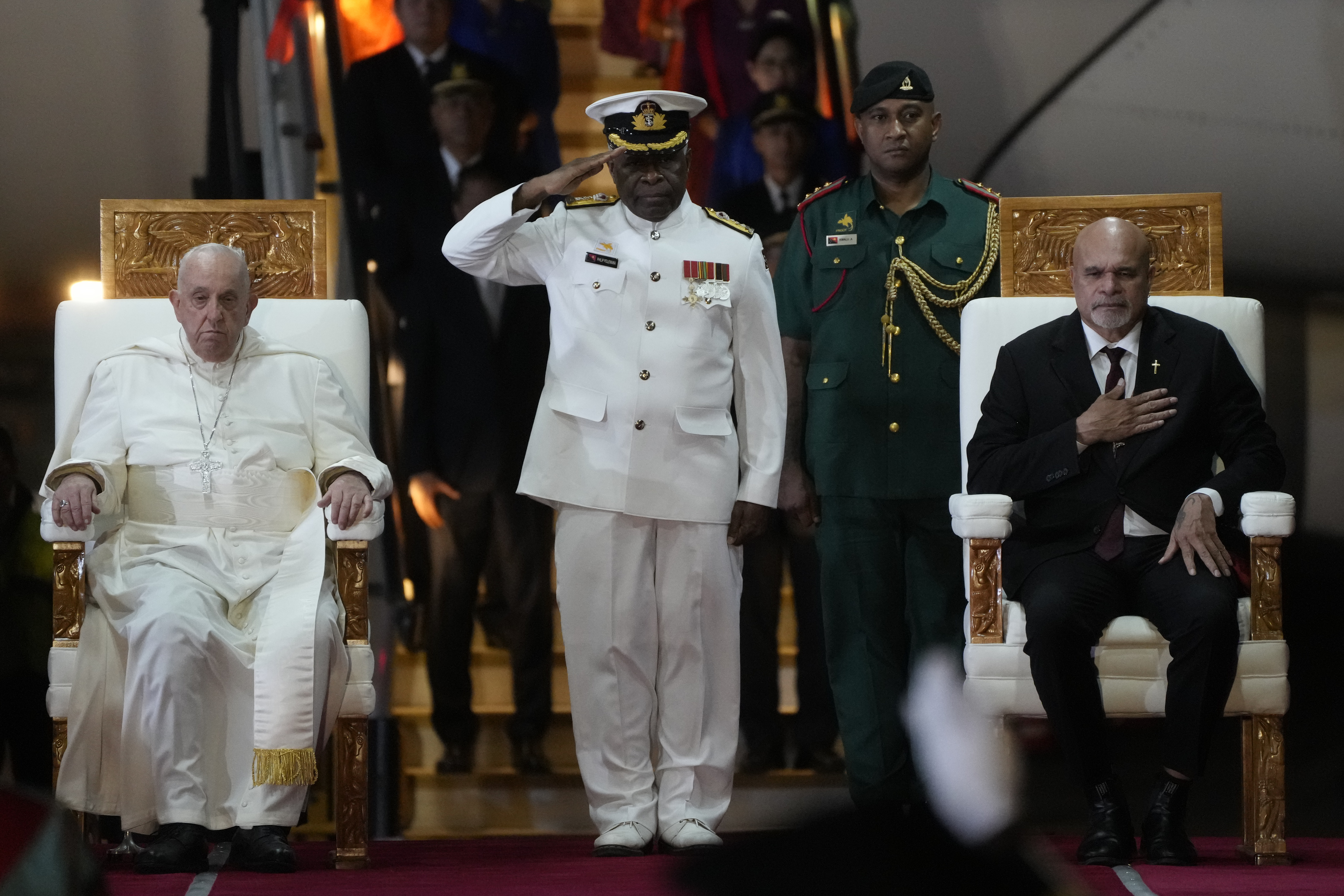 Pope Francis, left, is welcomed by Papua New Guinea's deputy Prime Minister John Rosso, right, and rear-Admiral Philip Polewara, center, as he arrives at Port Moresby's "Jackson" International Airport, Friday, Sept. 6, 2024. As a second leg of his 11-day trip to Asia and Oceania Pope Francis's visit to Papua New Guinea will take him to a remote part of the South Pacific island nation where Christianity is a recent addition to traditional spiritual beliefs developed over millennia.(AP Photo/Gregorio Borgia)