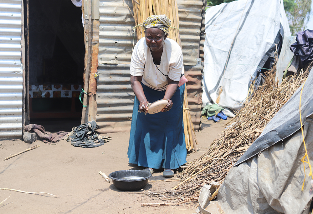 Florence Kadogo washes dishes outside her tent in Khumwanda displacement camp in Busia, a town in western Kenya on July 16. (GSR photo/Doreen Ajiambo)