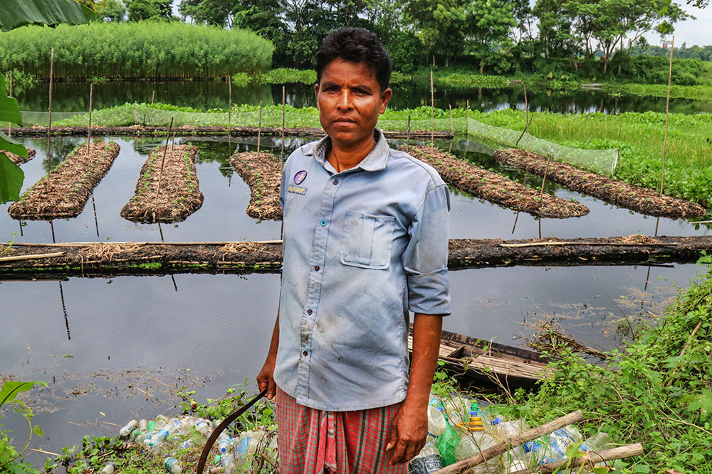 Tapan Biswas, a farmer who received training from Caritas Bangladesh, forms his floating beds using empty plastic bottles, which he ties together to form a platform he then covers in water hyacinth. (Stephan Uttom Rozario)