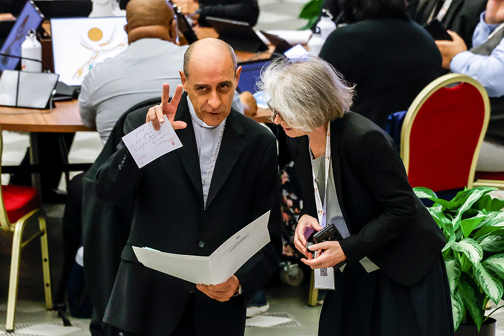 Cardinal Víctor Manuel Fernández, prefect of the Dicastery for the Doctrine of the Faith, speaks with Xavière Missionary Sr. Nathalie Becquart, undersecretary of the Synod of Bishops, before the start of a morning session of the synod in the Paul VI Audience Hall at the Vatican Oct. 21. (CNS/Lola Gomez)