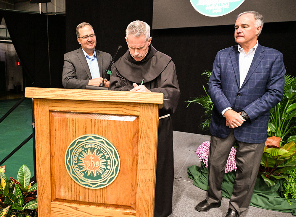 From left: Siena College President Charles Seifert, Franciscan Br. Michael Perry and Thomas Baldwin Jr., president of Siena's Board of Trustees, sign a resolution on sustainability, adopted by the board in March and publicly signed Oct. 11 as part of the college's integral ecology symposium. (Courtesy of Siena College)