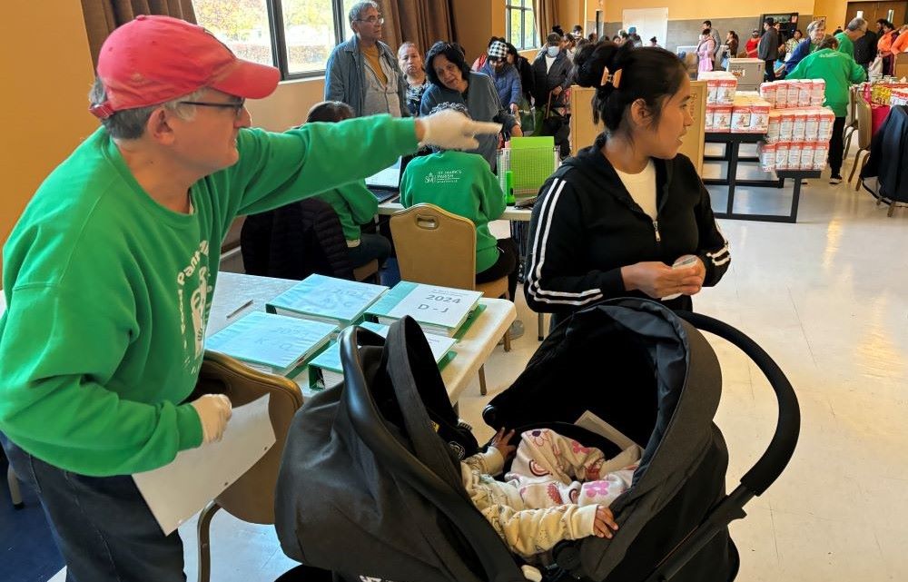 Larry Lojacono directs a pantry client to the food distribution at St. Mark the Evangelist parish. 