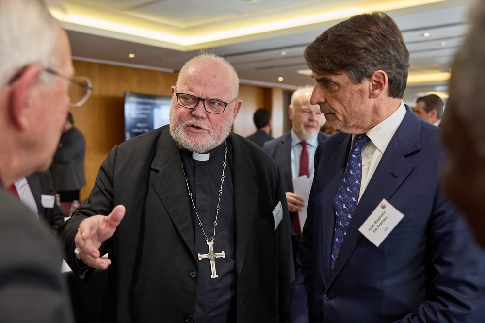 The cardinal wears plain black clerics and pectoral cross, de Franssu stands to his right wearing a navy suit.