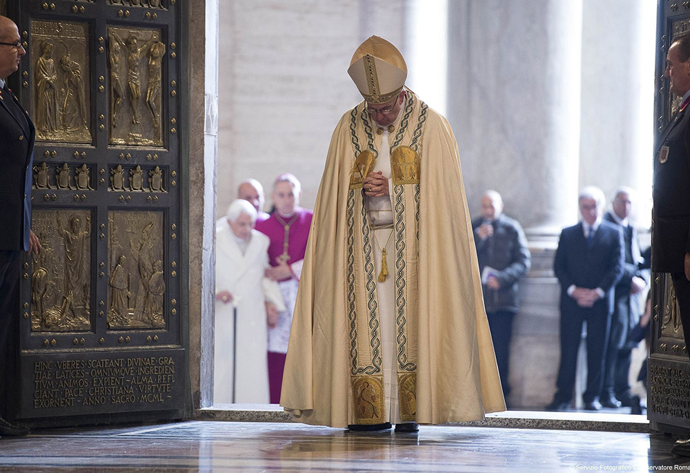 Pope Francis prays after walking through the Holy Door to inaugurate the Jubilee Year of Mercy in St. Peter's Basilica at the Vatican in this Dec. 8, 2015, file photo. In the background at left is retired Pope Benedict XVI. The pope has approved the theme, "Pilgrims of Hope," to be the motto for the Holy Year 2025. (CNS/Vatican Media)