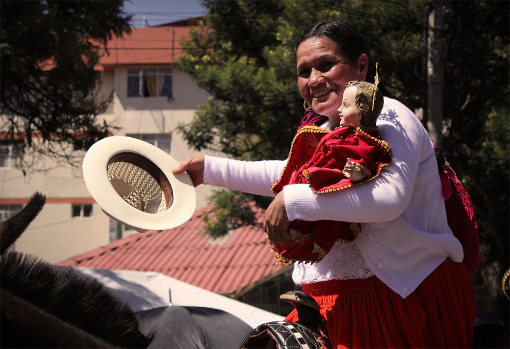 A woman is pictured with a reproduction of the image of the Niño Viajero (Traveling Child), during the 2013 Pase del Niño Viajero in Cuenca, Ecuador. (Wikimedia Commons/Jfbeltranr, CC BY-SA 4.0)