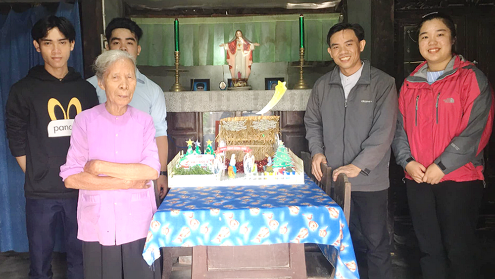 Ignatius Cao Tuan Duc, second from right, and other volunteers give a nativity scene and lanterns to Agnes Huynh Thi Nghiem, second from left, on Dec. 10. (Joachim Pham)