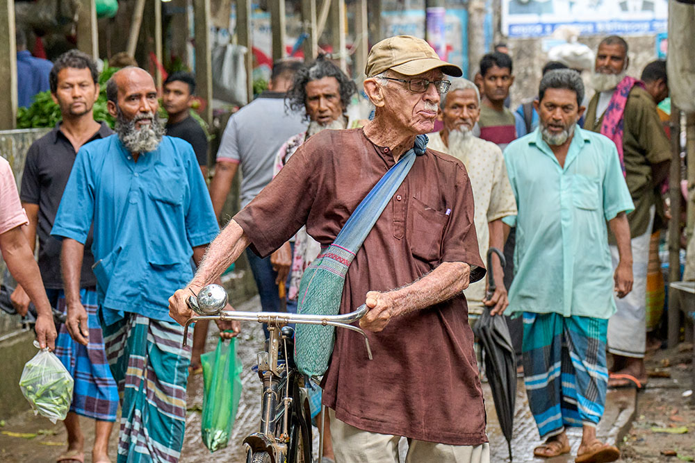 Maryknoll Fr. Bob McCahill walks his bike in May 2023 in Srinagar, Bangladesh, where he lives and serves the poor. (Paul Jeffrey)