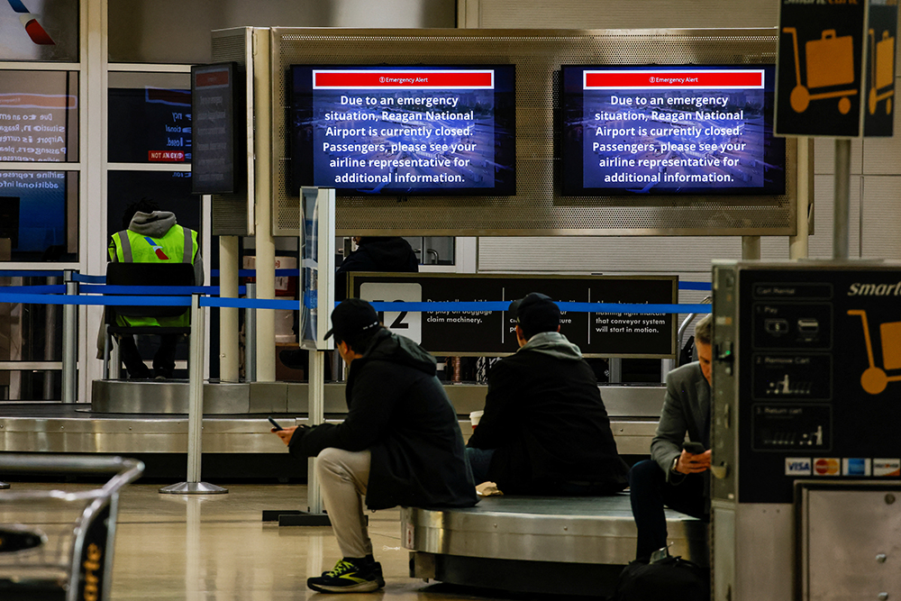 People sit at Ronald Reagan Washington National Airport, in the aftermath of the collision of American Eagle flight 5342 and a Black Hawk helicopter that crashed into the Potomac River, in Arlington, Virginia, U.S., Jan. 30, 2025. (Reuters/Eduardo Munoz)