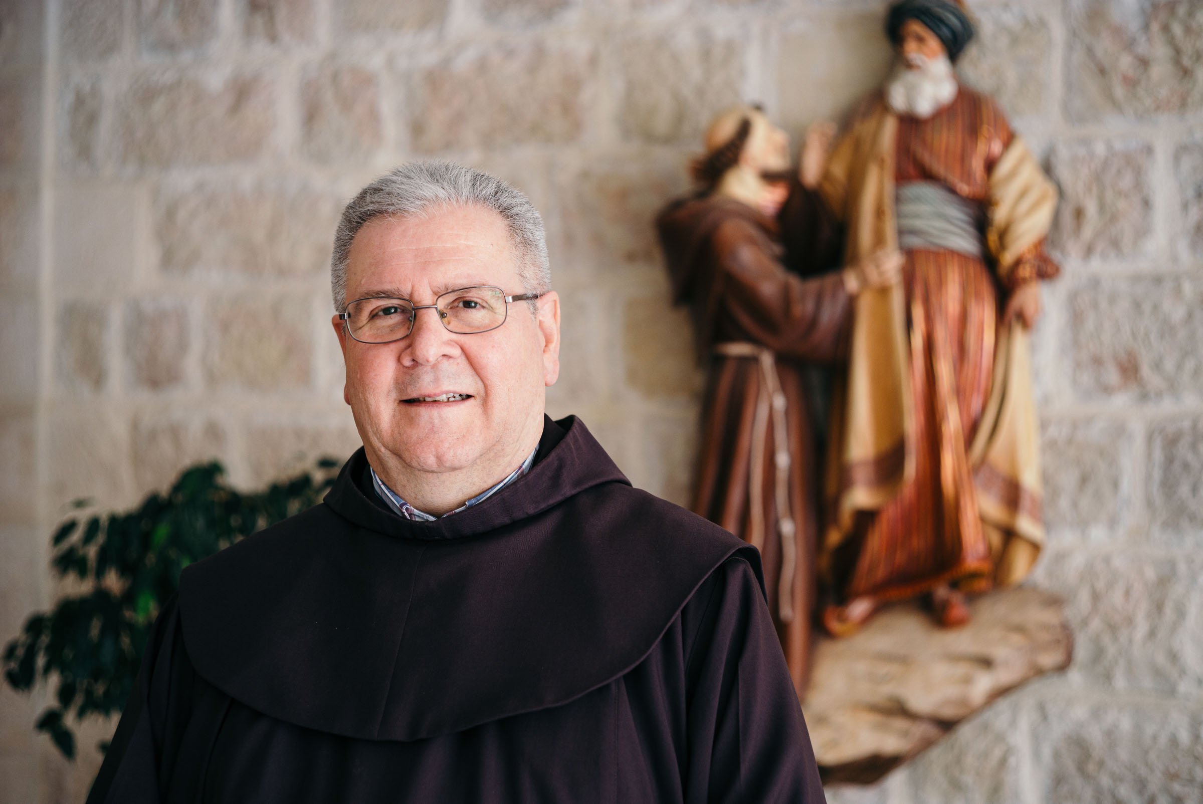 Patton wear habit and smiles in front of statue of St. Francis and the Sultan. 