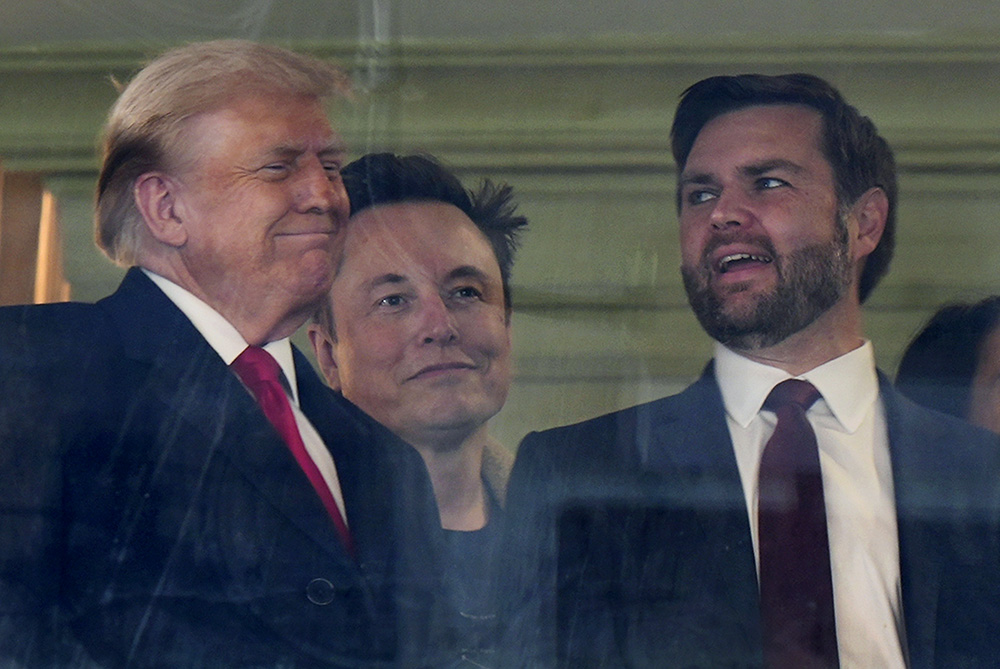 In this picture taken through a window, from left, President-elect Donald Trump, Elon Musk and Vice President-elect JD Vance attend the NCAA college football game between Army and Navy at Northwest Stadium in Landover, Md., Dec. 14, 2024. (AP/Stephanie Scarbrough)