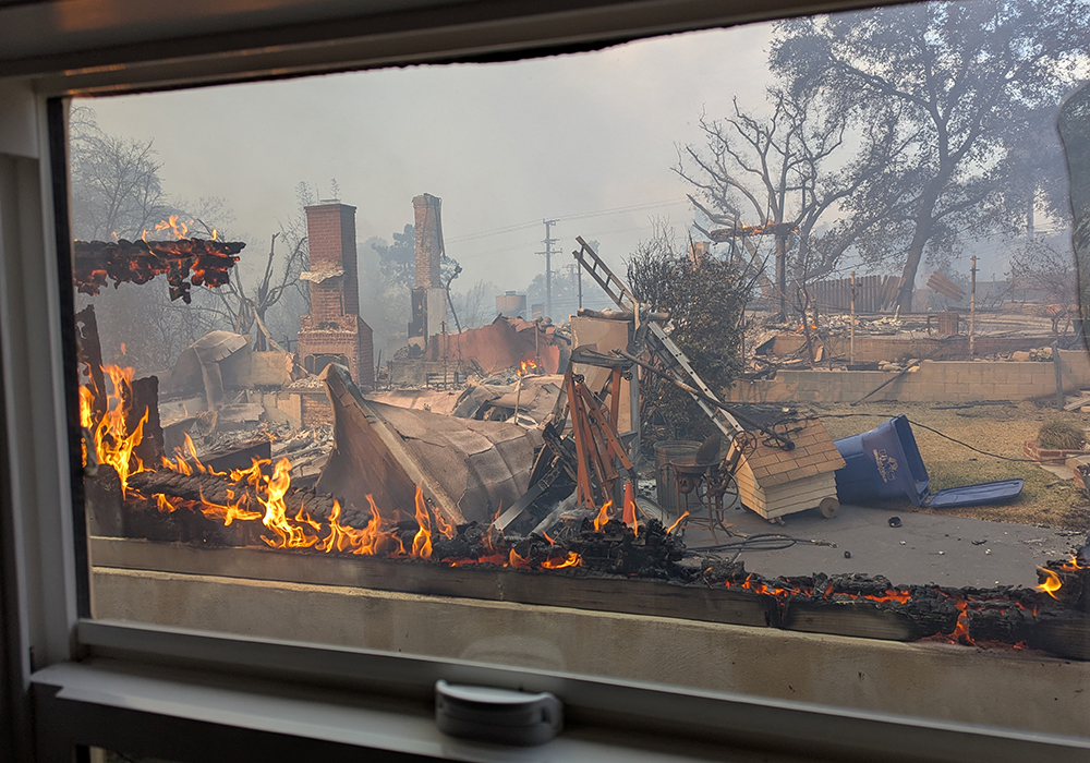 Fire and damage is seen outside a window on Jan. 8. With fire on three sides, "We should not have been in there," Nick later told NCR. But their home was about to catch fire, so he looked at the house and said, "We can do this." (Nick Norman)