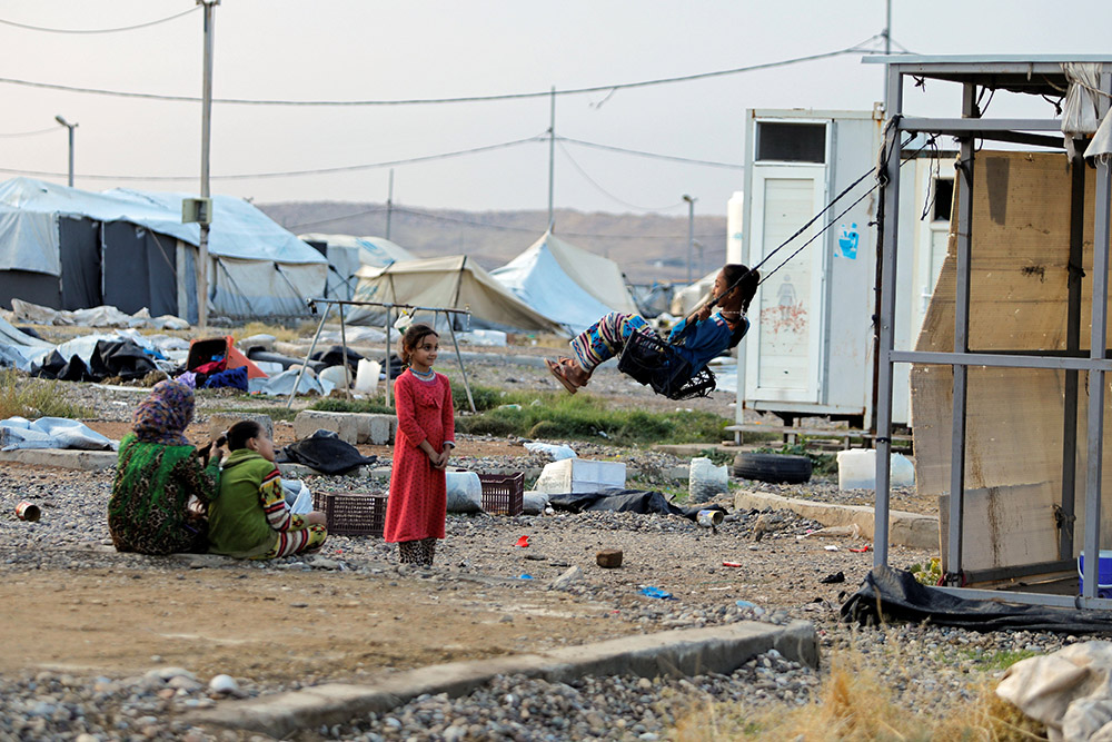 A girl near Mosul, Iraq, plays on a makeshift swing at Hammam Al-Alil camp where displaced Iraqis prepare to be evacuated Nov. 10, 2020. (CNS/Reuters/Abdullah Rashid)