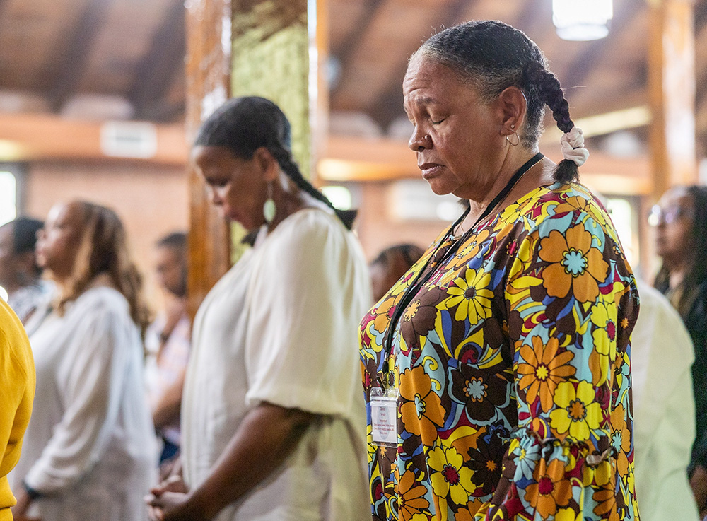 From left, family members Bernadette Semple (in the background), Toni Ann Semple and Denise Semple pray during Mass Sept. 3, 2023, at St. Peter Claver Church in St. Inigoes, Md. The Mass closed the Southern Maryland GU272 — Jesuit Enslaved Descendant Gathering Aug. 31-Sept. 3 that year. (OSV News/Catholic Standard/ Mihoko Owada)