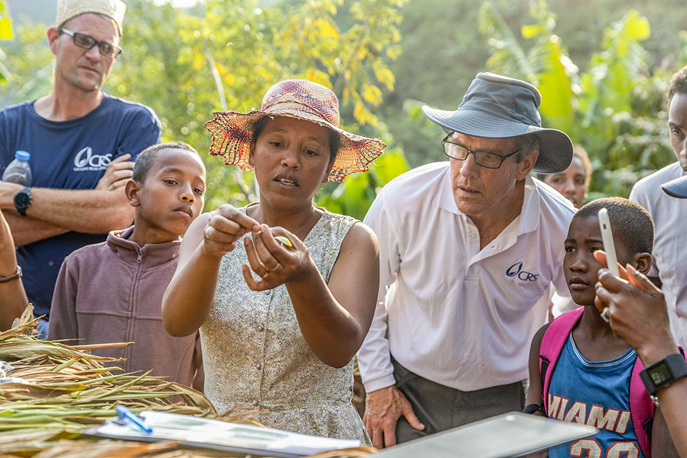 Félicité Raminosoa shows Sean Callahan, president and CEO of Catholic Relief Services, in gray hat, how to hand pollinate vanilla at her vanilla farm in Ifanadiana, Madagascar, Nov. 2, 2022. (OSV New/CRS/Laura Elizabeth Pohl)