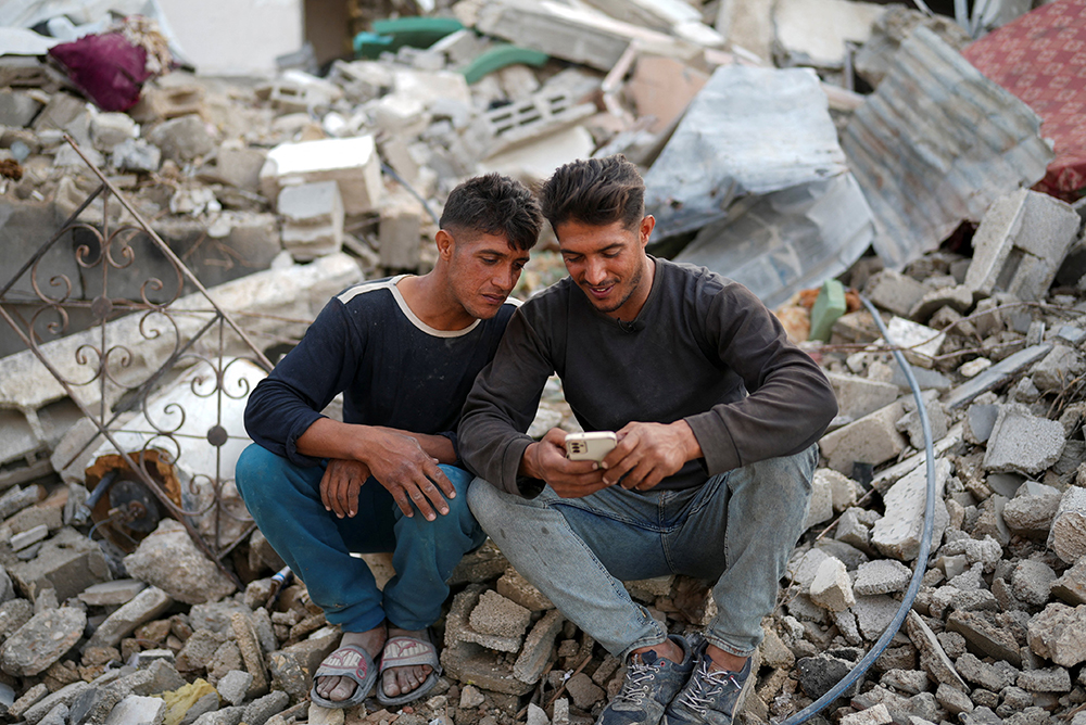 Palestinian twins Mahmoud and Ibrahim Al-Atout sit amid the rubble of their destroyed house after being reunited, in Jabalia, northern Gaza Strip, Jan. 29, 2025, following the ceasefire between Israel and Hamas,. The brothers were separated during the war when Ibrahim was displaced to the southern part of Gaza at Israel's order. (OSV News/Retuers/Osama Al-Arabid)