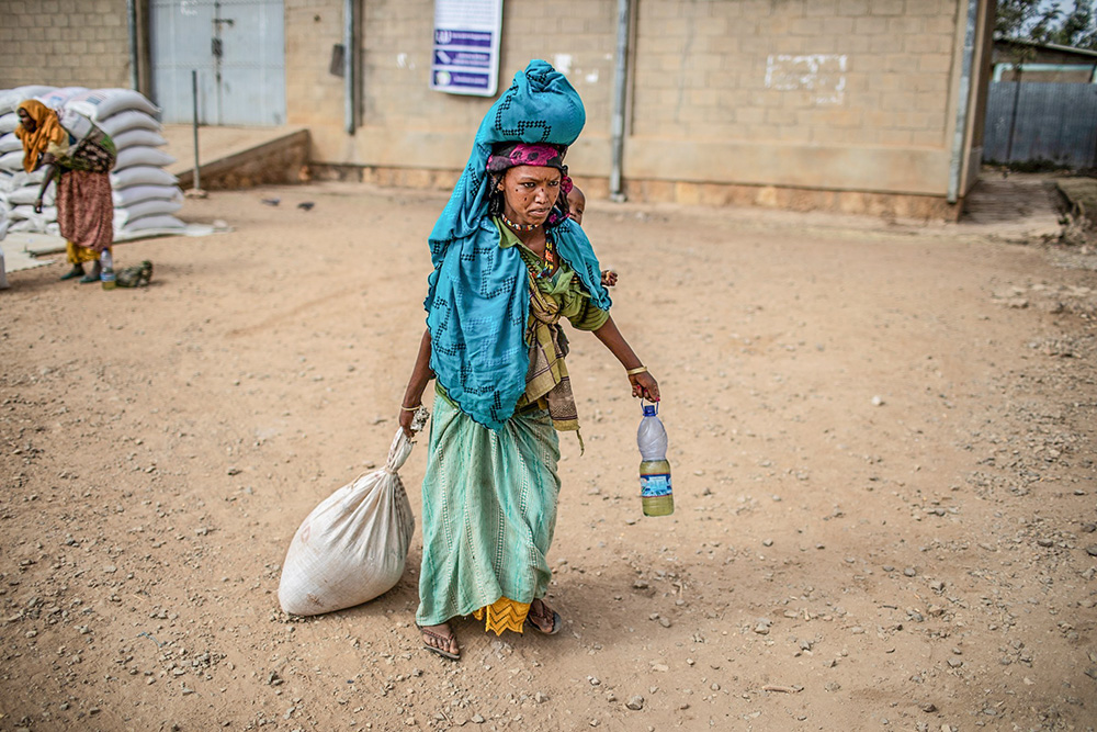 A woman carries home her rations of wheat, yellow split peas and cooking oil following a distribution of U.S. Agency for International Development (USAID) food in a rural area of Ethiopia's Oromia region Feb. 9, 2019. (OSV News/Courtesy of CRS/Will Baxter)