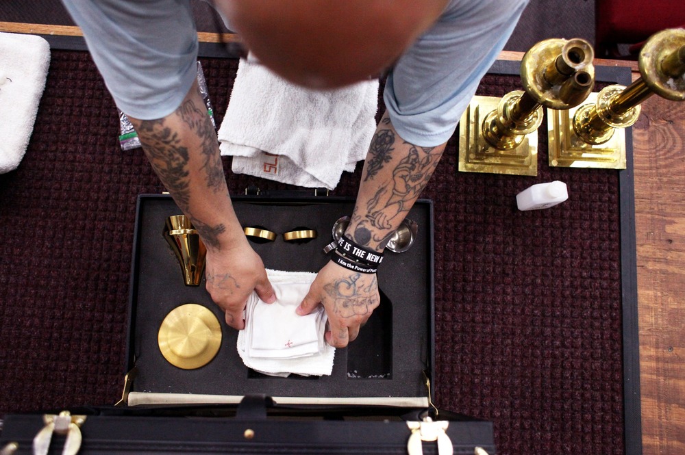 Only the inmate's arms and hands are visible, from above, folding a small altar cloth.