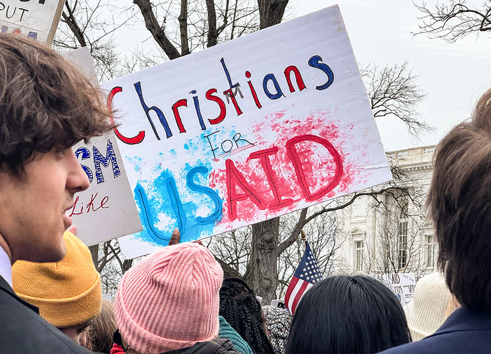 A woman waves a "Christians for USAID" poster Feb. 5, 2025, at a rally near the U.S. Capitol supporting the U.S. Agency for International Development, known as USAID. The agency, a top funder of Catholic Relief Services and other humanitarian work worldwide, is under threat as the Trump administration moves to dismantle it. (NCR photo/Rhina Guidos)