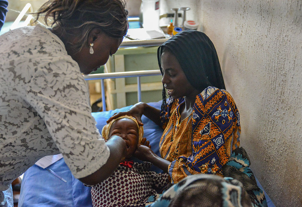 Sa'adatu cries as a nurse at the Hope for the Village Child Foundation clinic attends to her. (Patrick Egwu)