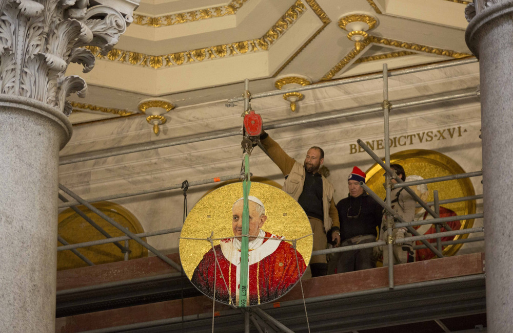 A man hangs a medallion from an elevated balcony.