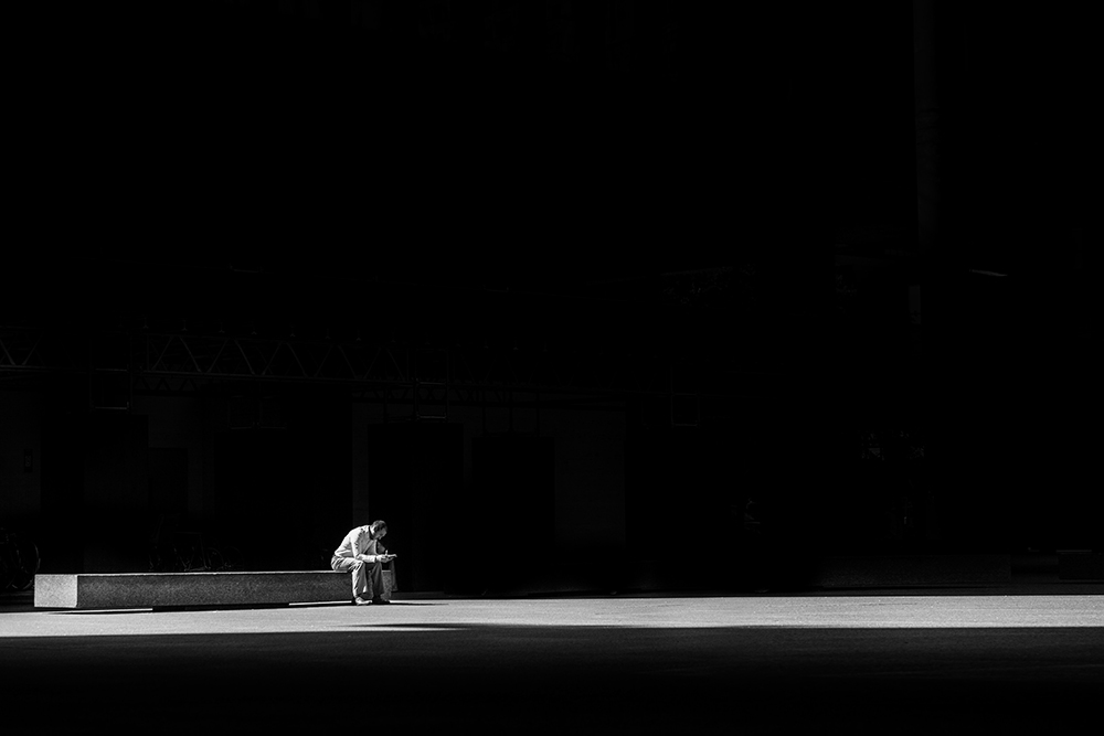 A person sitting alone in a dark room (Unsplash/Matthew Henry)