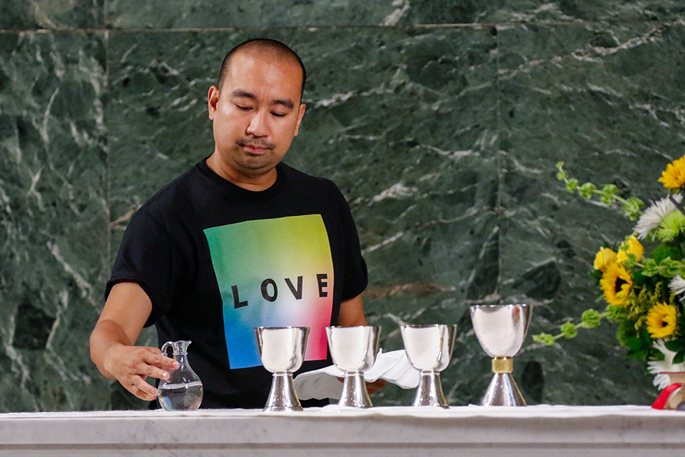 Altar server Angelo Alcasabas prepares the altar during an annual "Pre-Pride Festive Mass" at St. Francis of Assisi Church in New York City on June 29, 2019. (CNS/Gregory A. Shemitz)