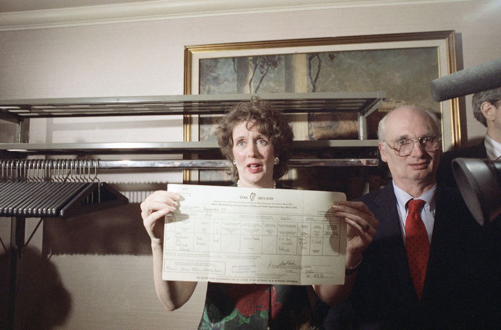 Woman holds up birth certificate at press conference.