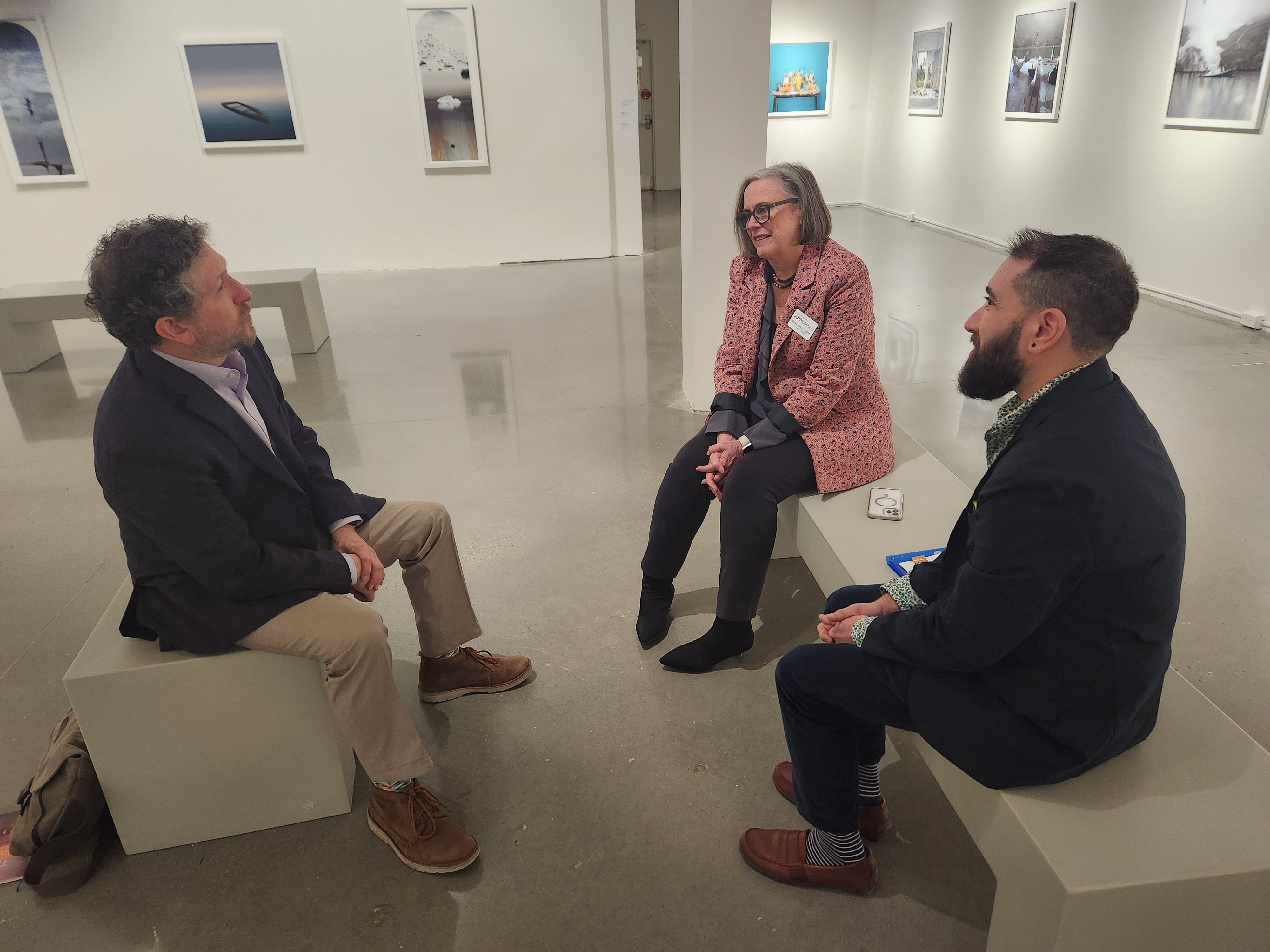 three people on benches in art gallery