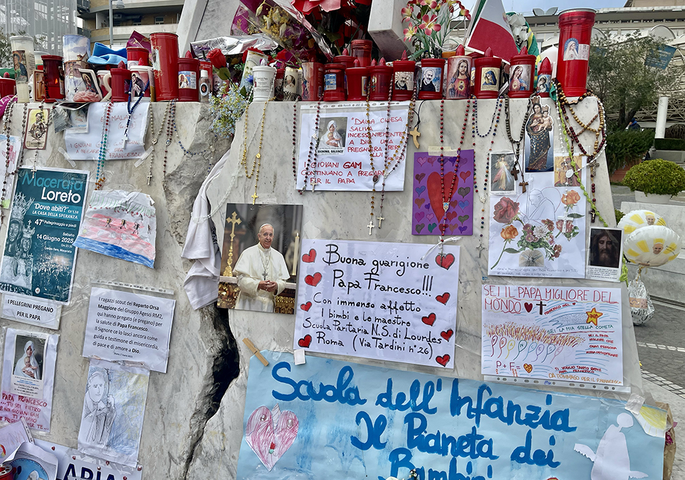 The statue of St. John Paul II at Gemelli Hospital is surrounded by dozens of candles, hanging rosaries and drawings or photographs of Pope Francis with messages of all sizes, shapes and colors, wishing him a speedy recovery. (NCR photo/Camillo Barone)