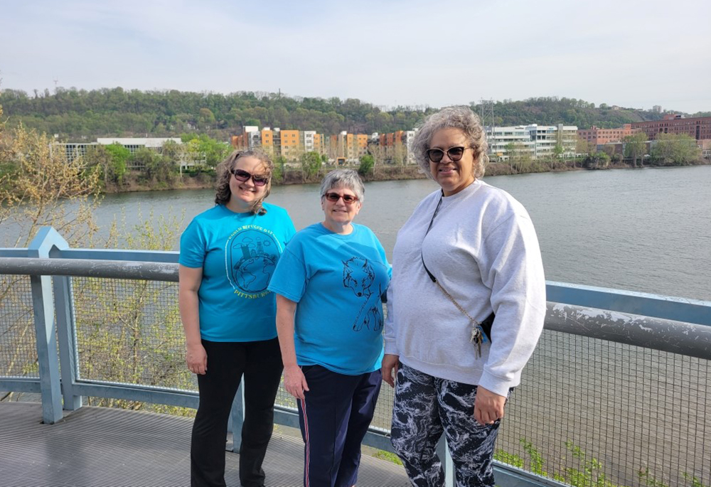 Sr. Caryn Crook, center, is pictured with friends on a walking trail near the House of Discernment, with a view of Pittsburgh across the Allegheny River. (Courtesy of Caryn Crook)