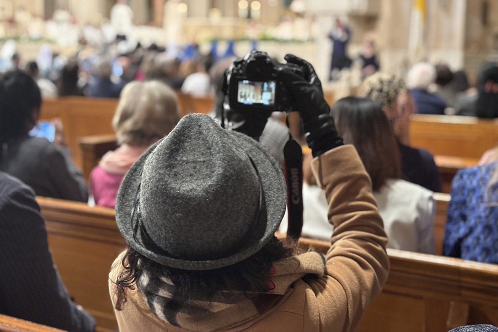 A person in the congregation takes a photo during the installation Mass March 11 of Washington Cardinal Robert McElroy at the Basilica of the Shrine of the Immaculate Conception. (NCR photo/James V. Grimaldi)