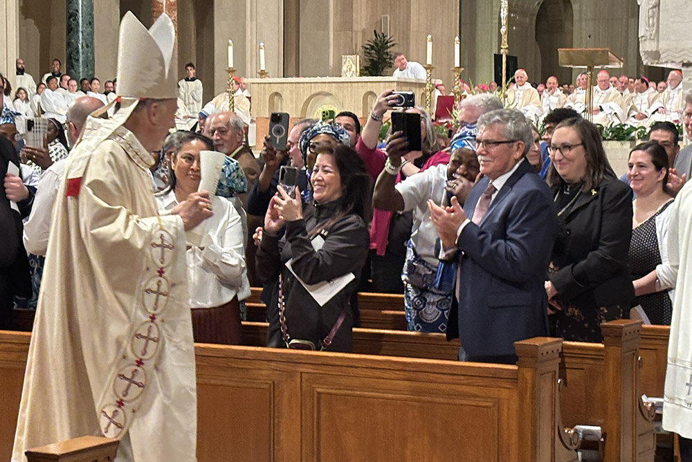 Washington Cardinal Robert McElroy acknowledges some of those in the congregation as he walks past pews in the opening procession of his installation Mass March 11 at the Basilica of the Shrine of the Immaculate Conception. (NCR photo/James V. Grimaldi)